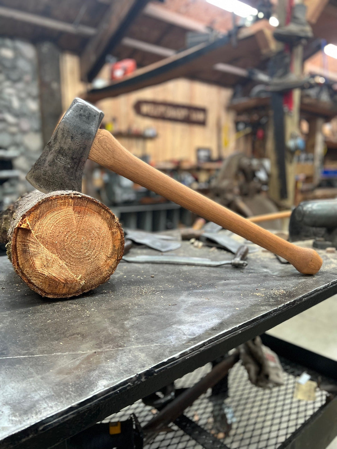 A close-up of a natural hickory wood axe handle with a textured grip, ready for use in logging tasks